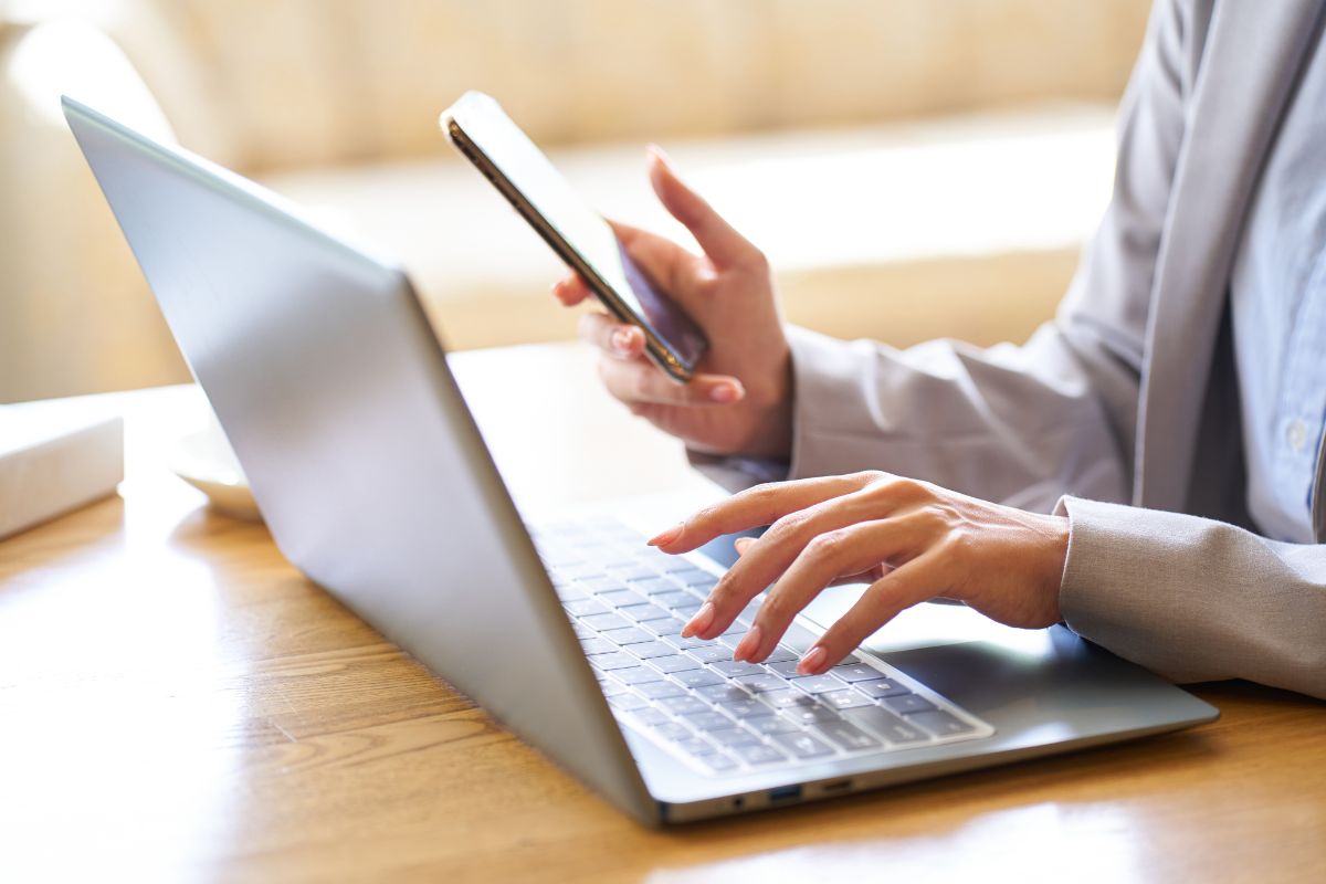 Corretor de seguros atendendo clientes pela internet usando notebook e celular