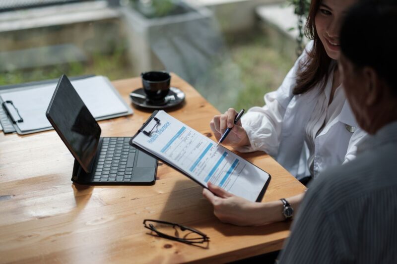 Corretor de seguros mostrando proposta personalizada a cliente empresarial.